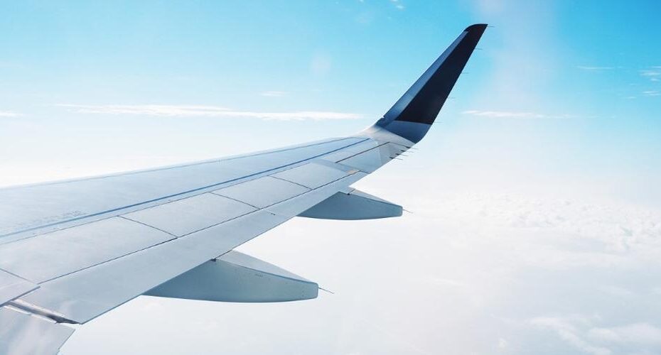 A view of an airplane wing flying over clouds, illustrating the importance of medical examinations for pilots at Clinique Omicron.