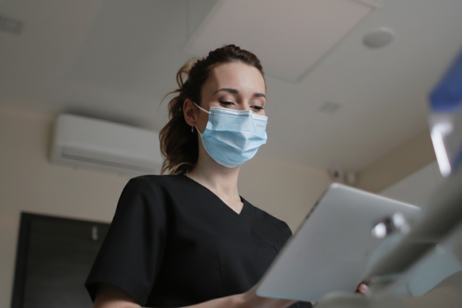 Infirmière en tenue médicale utilisant une tablette dans un environnement de soins, illustrant l'autonomie et l'expertise des soins infirmiers à la Clinique Omicron.