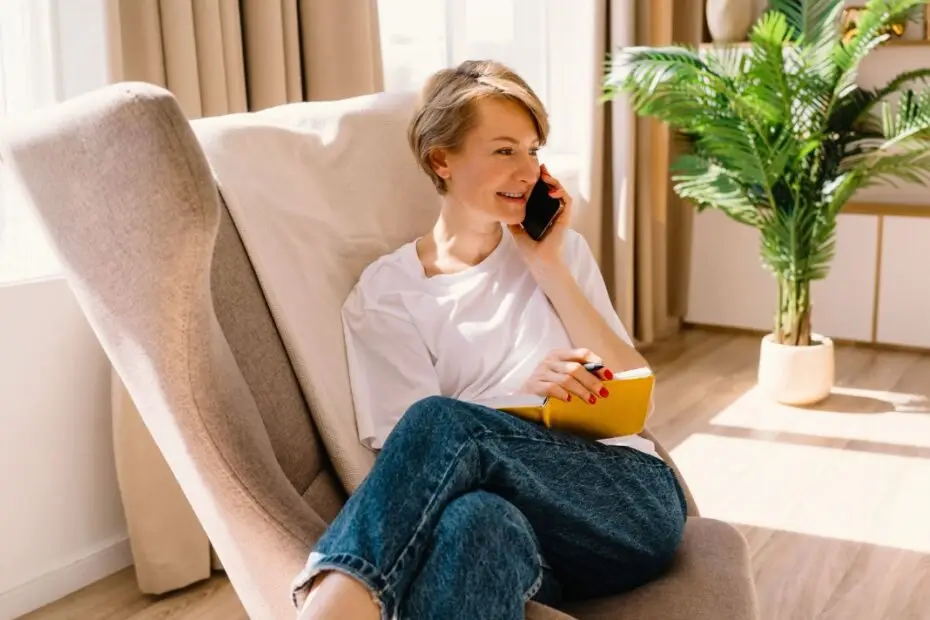 Femme souriante au téléphone dans un environnement confortable, illustrant le soutien psychologique et la consultation à distance pour la santé mentale.