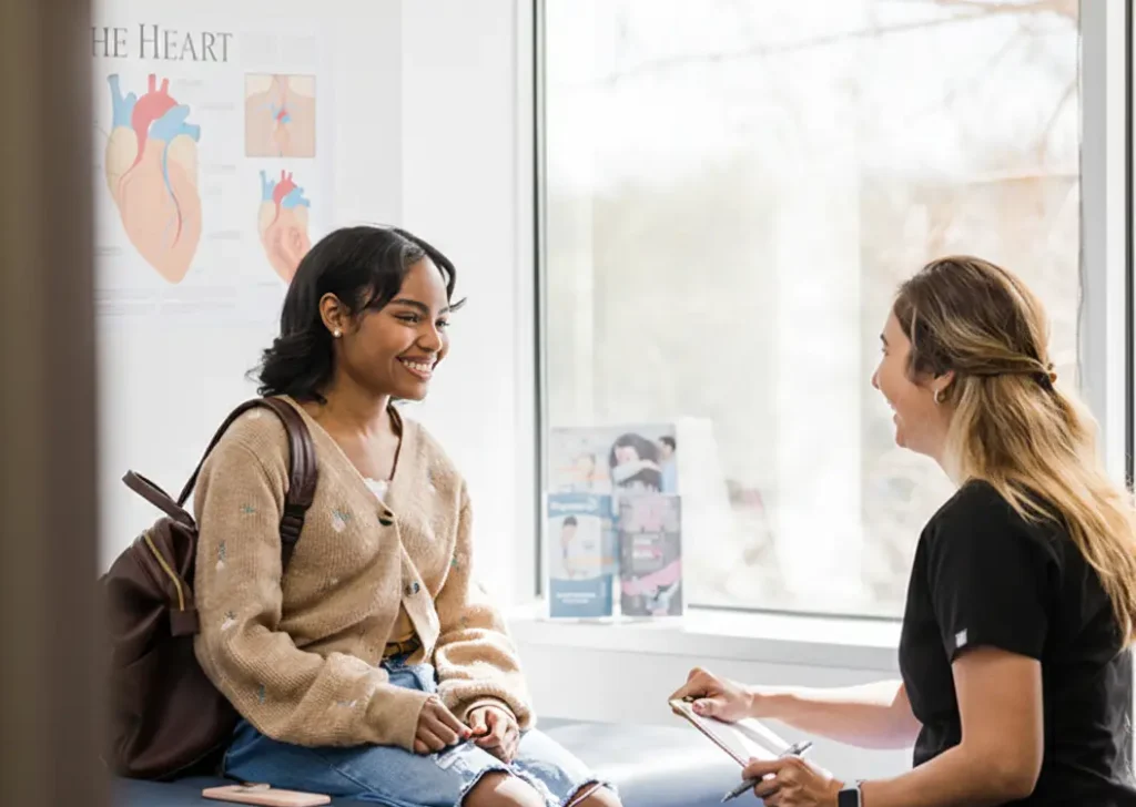 Smiling woman in medical consultation with a health professional, anatomical posters in background, reassuring, modern atmosphere.