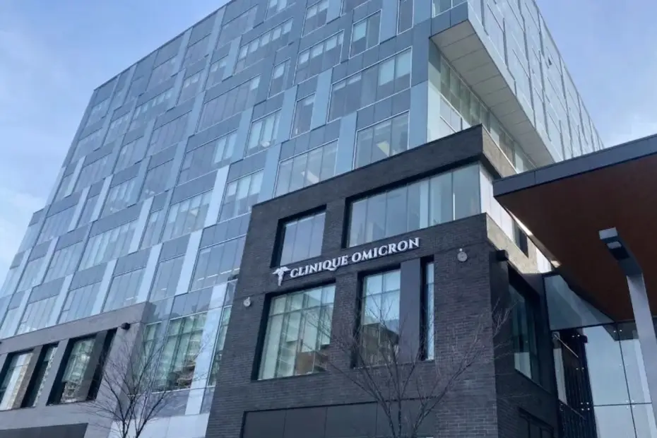 Clinique Omicron, b&acirc;timent moderne en verre et brique, fa&ccedil;ade accueillante avec logo, soulignant l'accessibilit&eacute; des soins de sant&eacute; au Qu&eacute;bec.