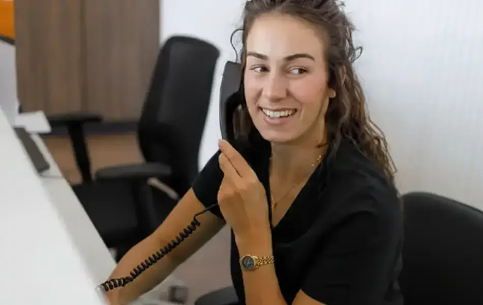 Réceptionniste souriante répondant au téléphone au bureau d'accueil d'une clinique