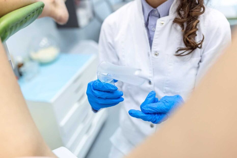 Gloved hands holding a clear contact lens in a clinical setting.